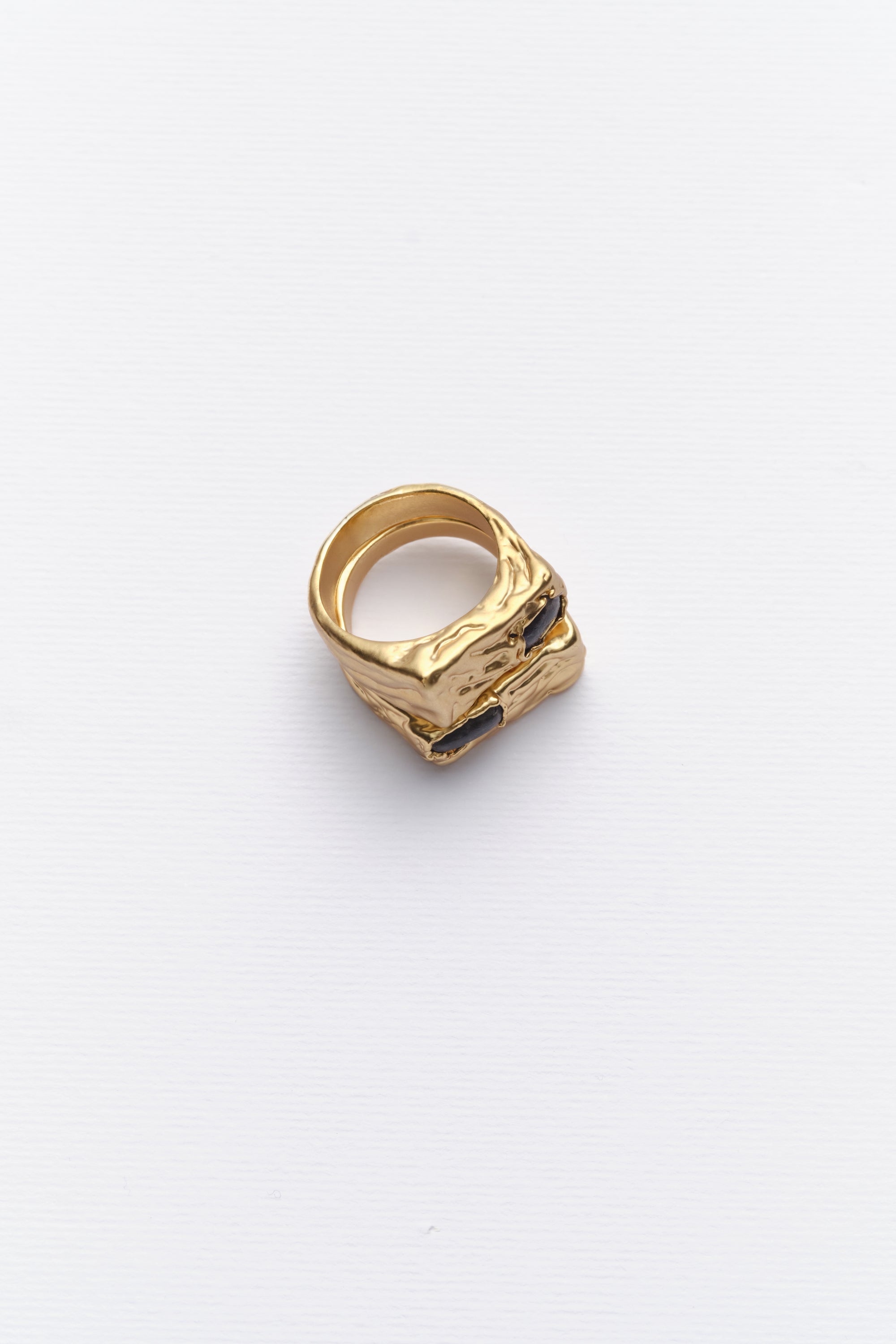 Gold sculptural signet ring with dark stone angled view
