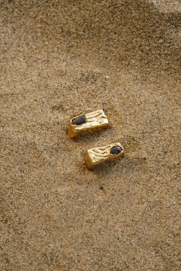 Gold textured signet rings styled on sand