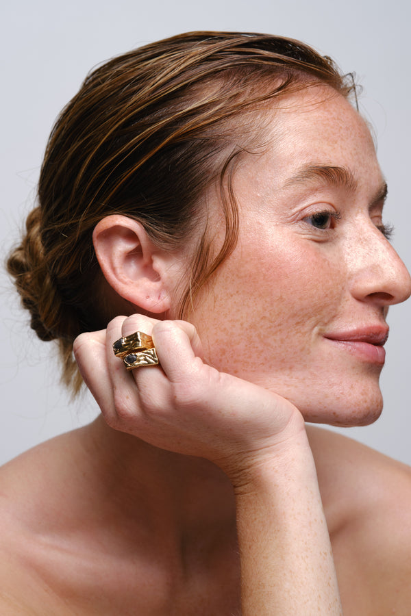 Gold sculptural signet ring worn on model portrait