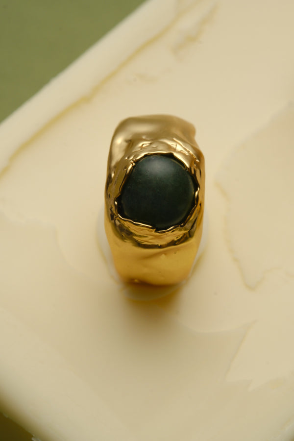 Close-up of gold signet ring with green gemstone