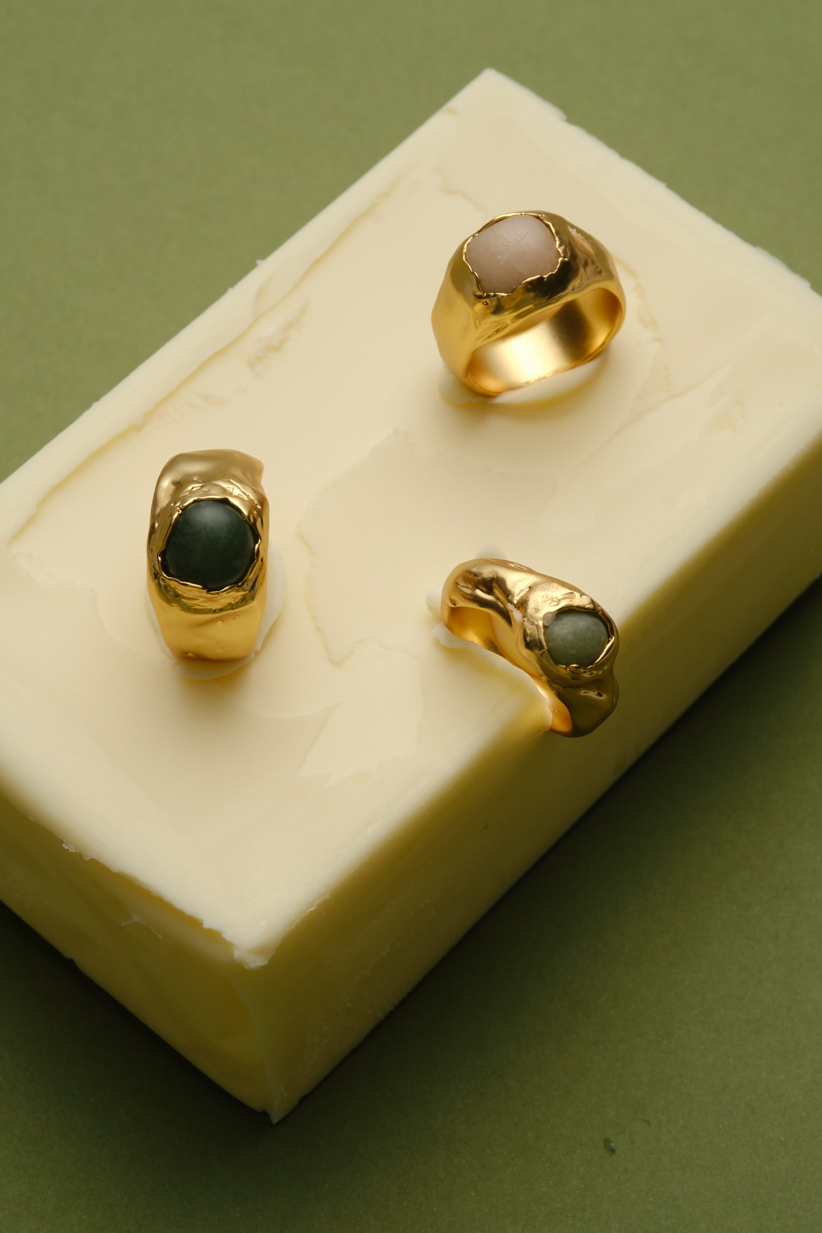Gold organic gemstone rings displayed on marble block