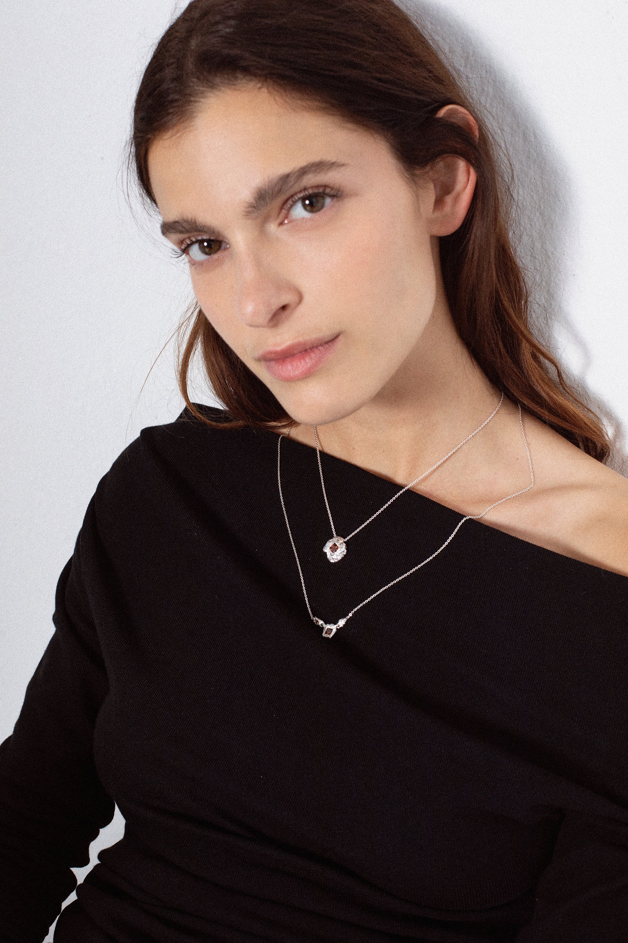 Silver textured round pendant necklace with red gemstone on model portrait