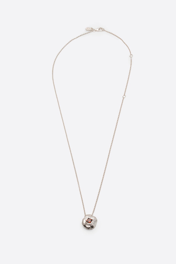Silver textured round pendant necklace with square red gemstone flat lay