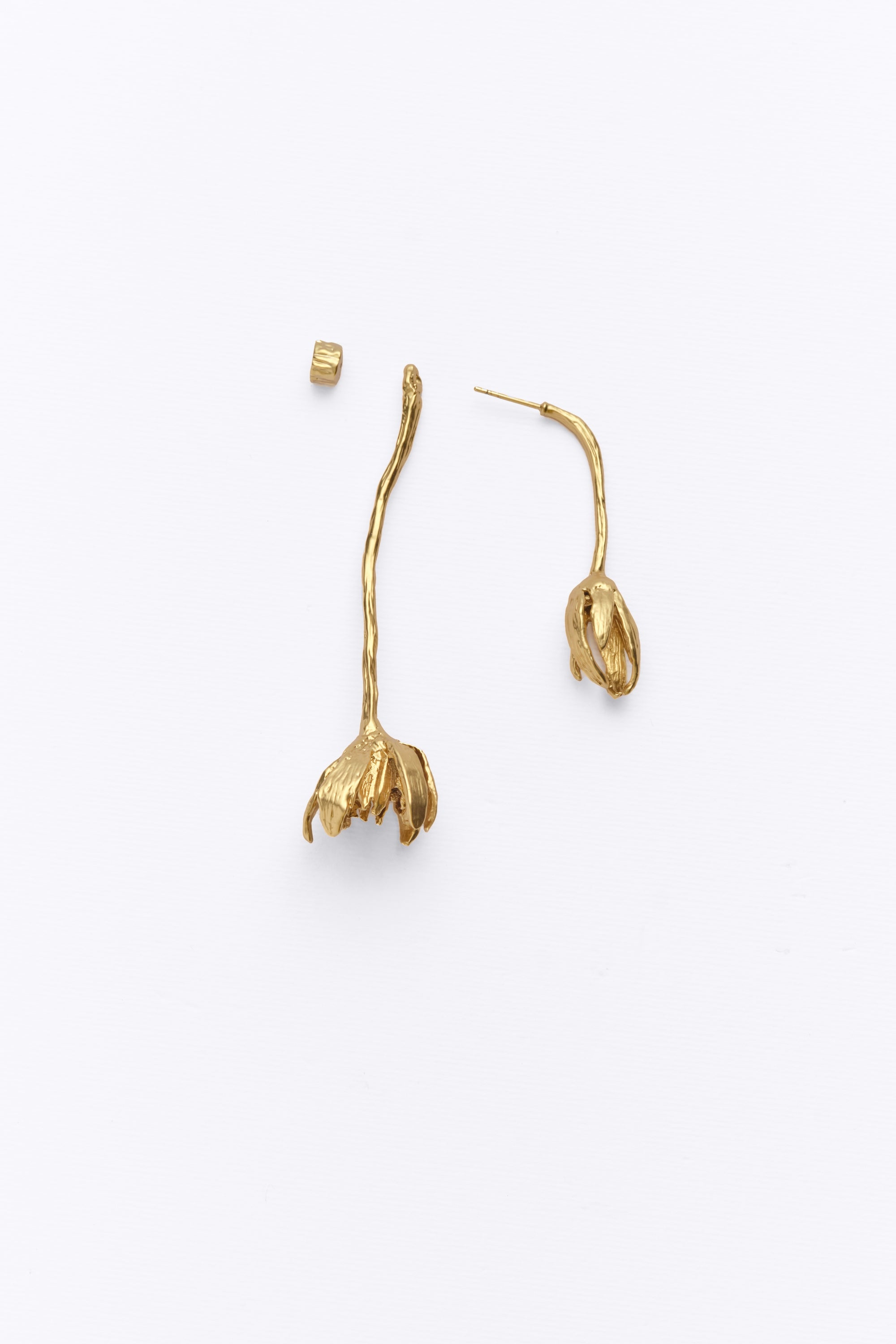 Gold sculptural flower drop earrings flat lay