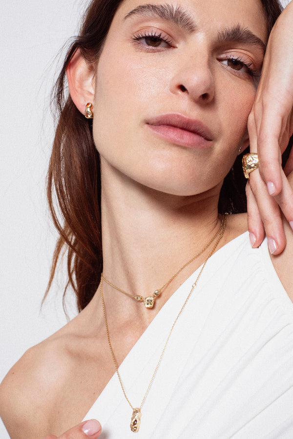 Layered gold textured elongated pendant necklace on model