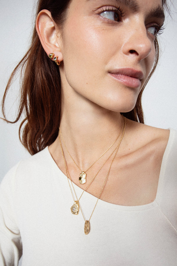 Layered gold textured pendant necklaces worn on model