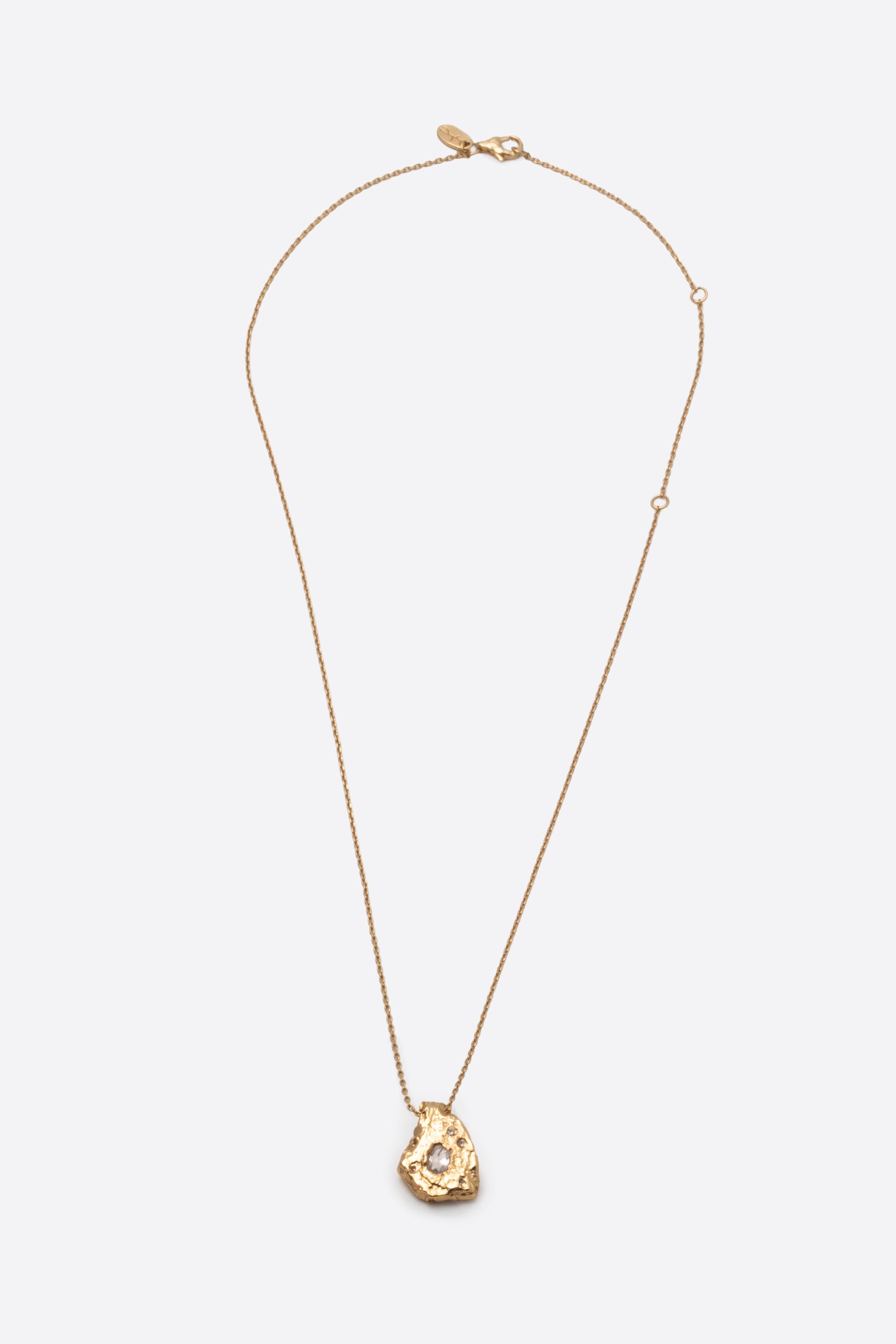 Gold textured organic pendant necklace with clear gemstone flat lay