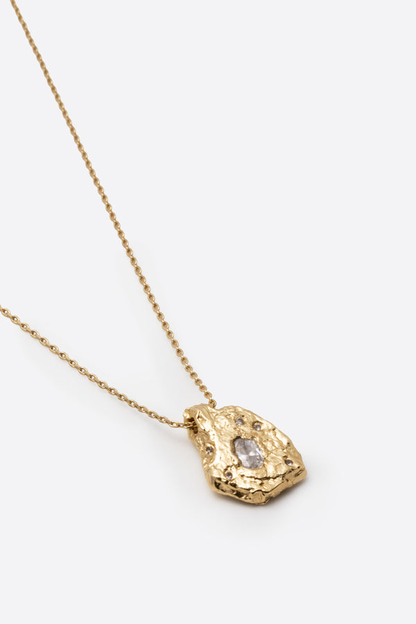 Detail of gold textured organic pendant with clear gemstone
