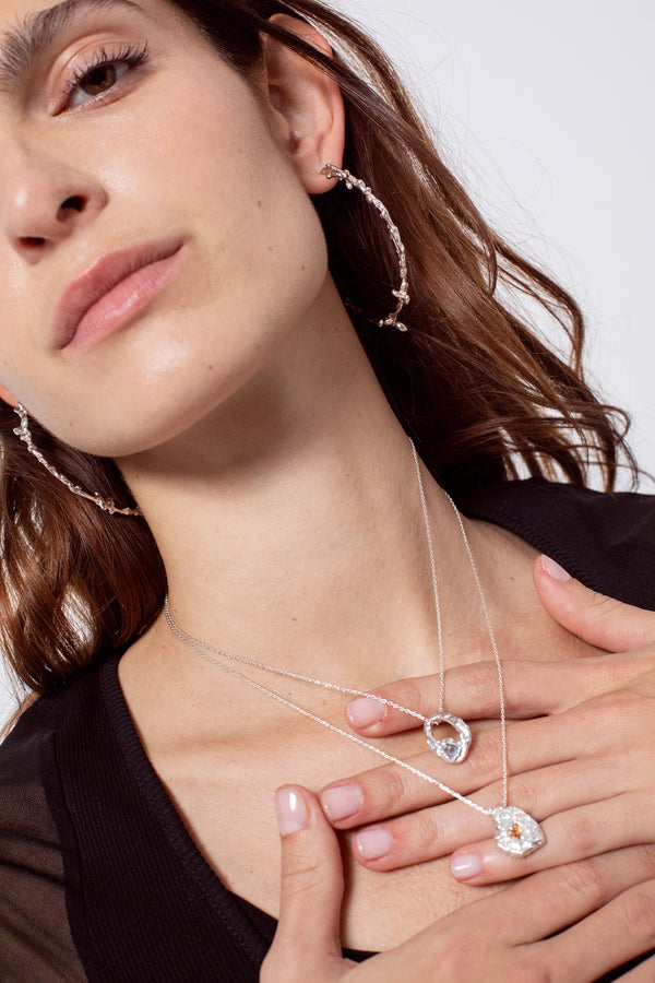 Layered silver textured pendant necklaces worn on model