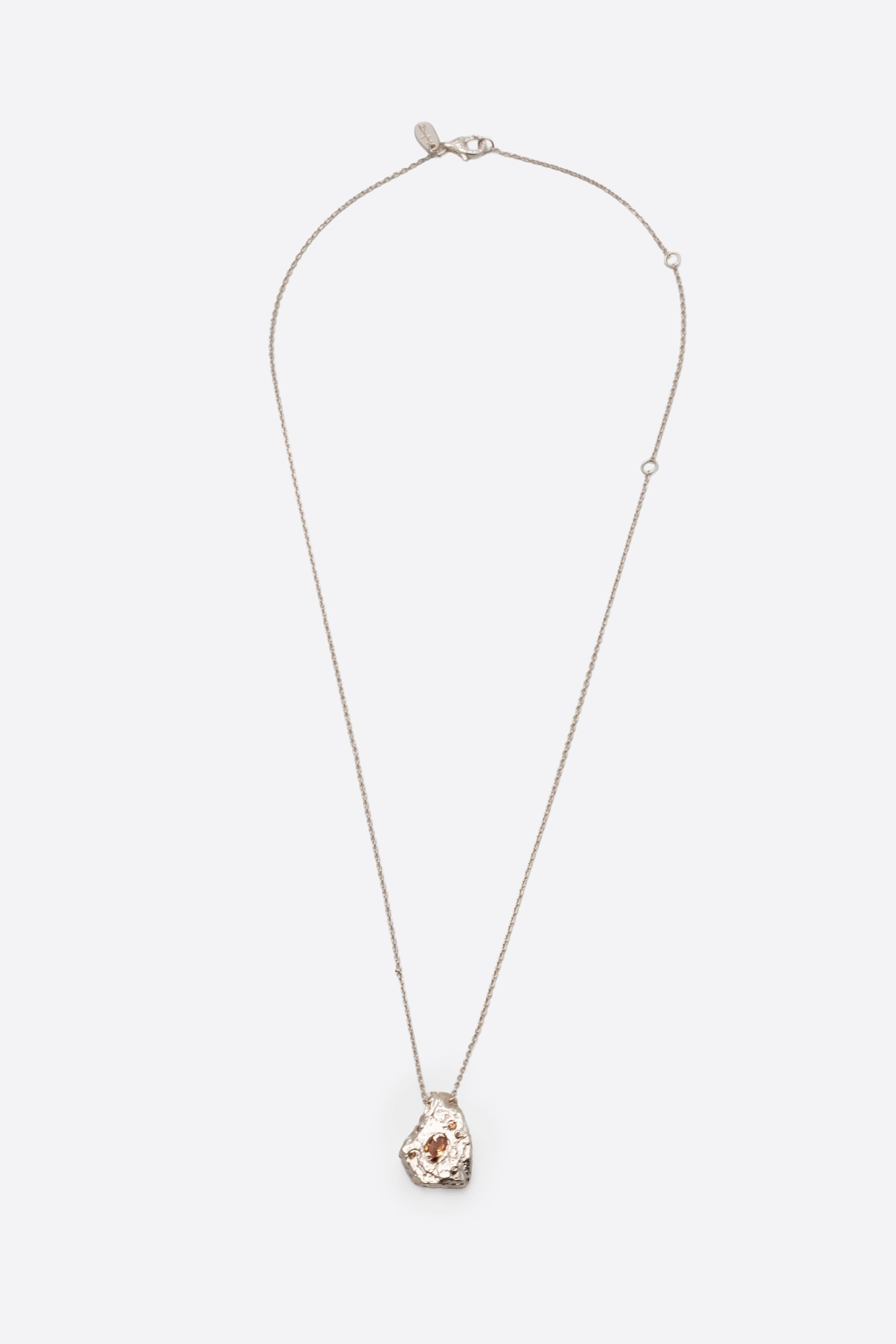 Silver textured organic pendant necklace with clear gemstone flat lay