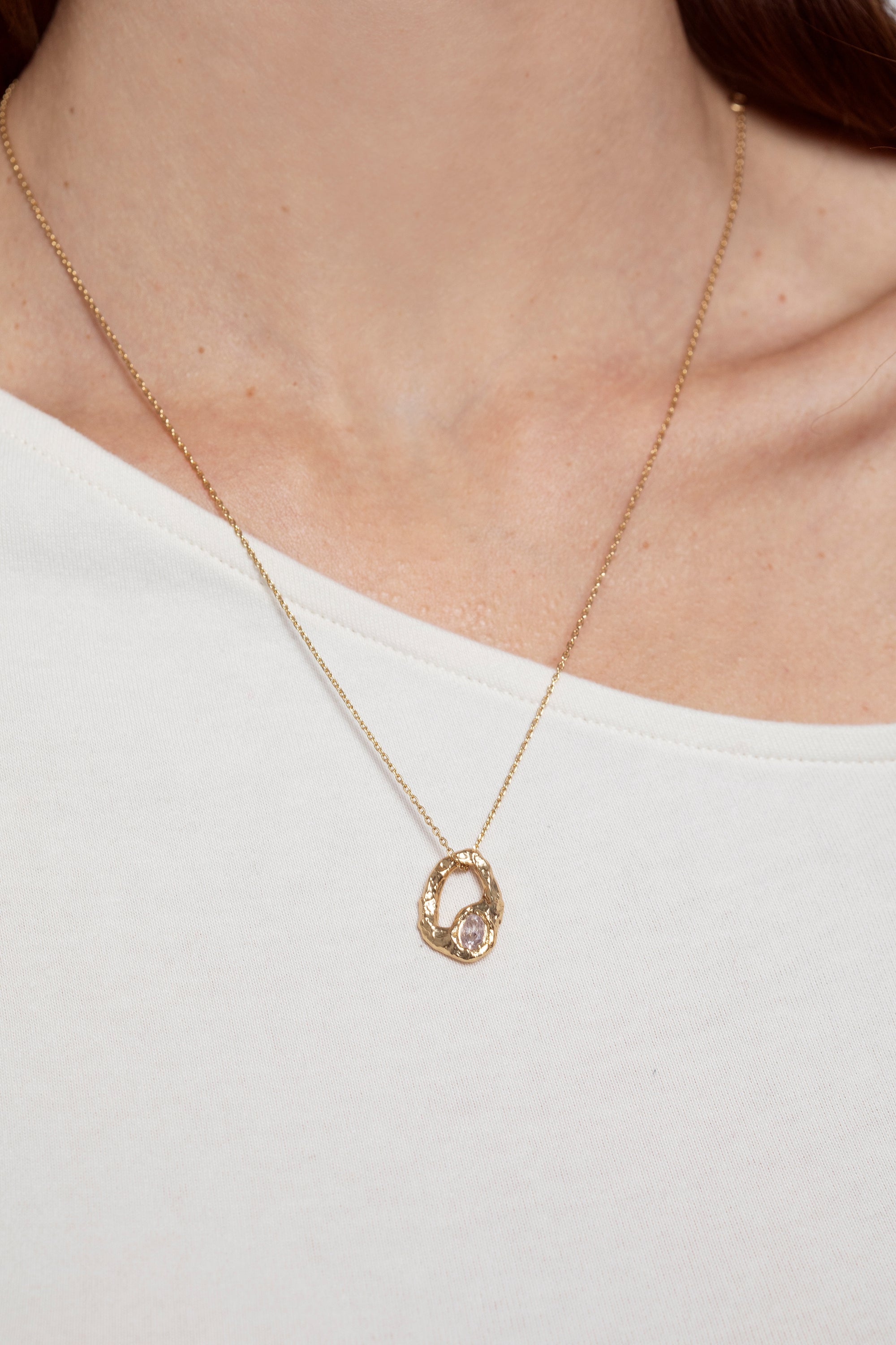 Gold textured open heart pendant necklace with oval stone worn on model