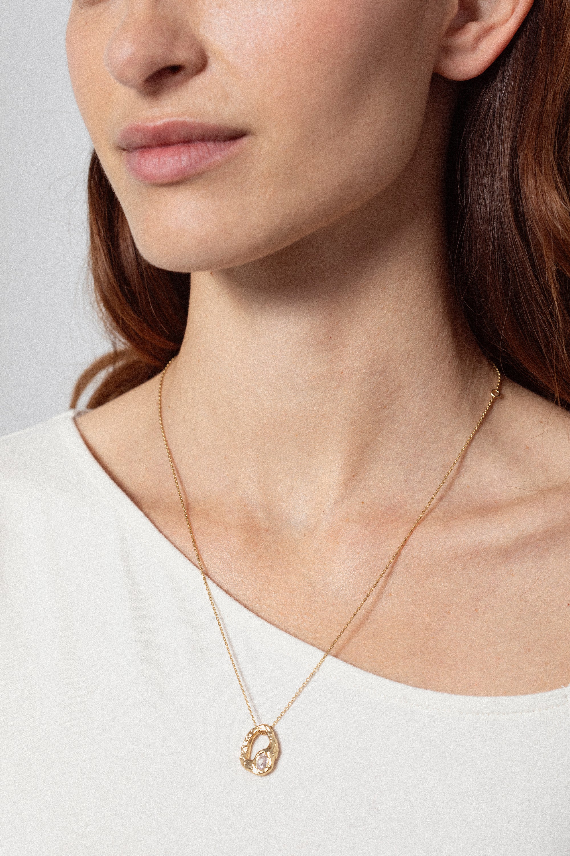 Gold textured open heart pendant necklace with oval stone worn on model close-up