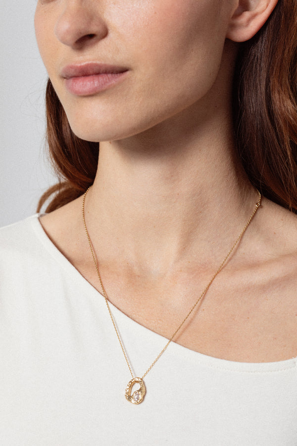 Gold textured open heart pendant necklace with oval stone worn on model close-up