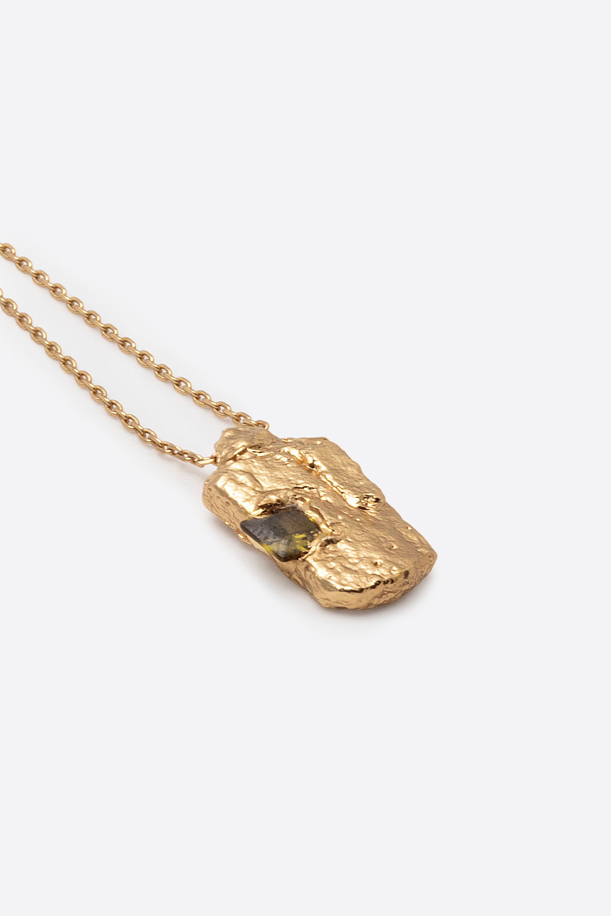 Detail of gold textured rectangular pendant with inset dark gemstone