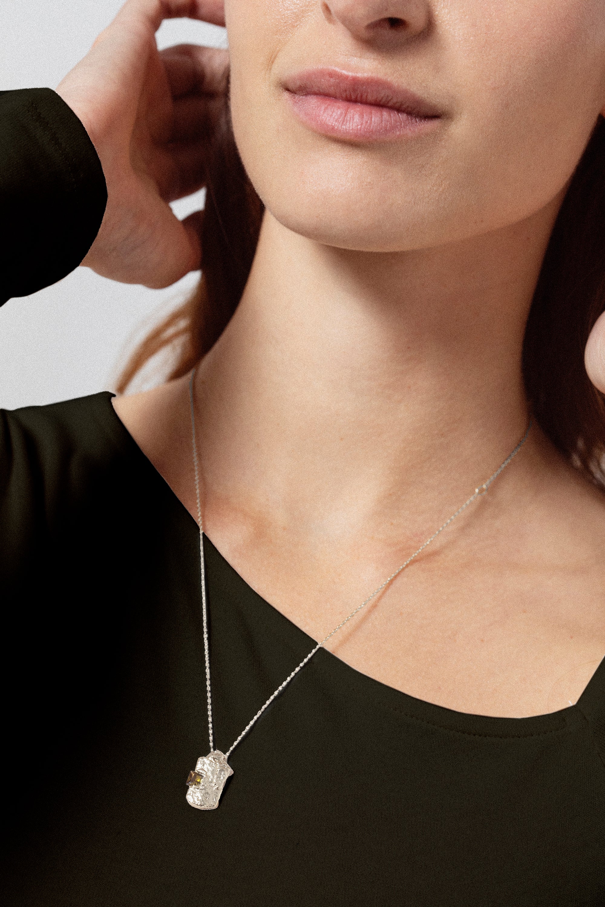 Silver textured rectangular pendant necklace with yellow gemstone worn on model
