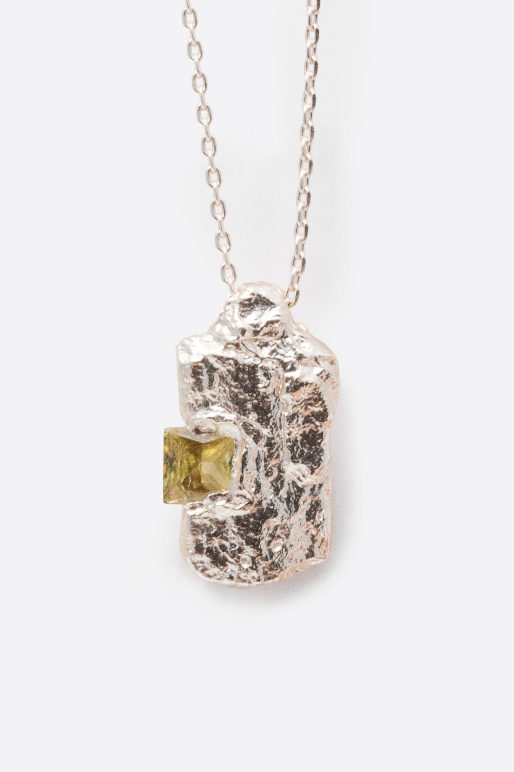 Detail of silver textured rectangular pendant with inset yellow gemstone