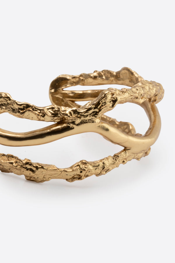 Close-up of sculptural gold cuff bracelet with intertwined organic design