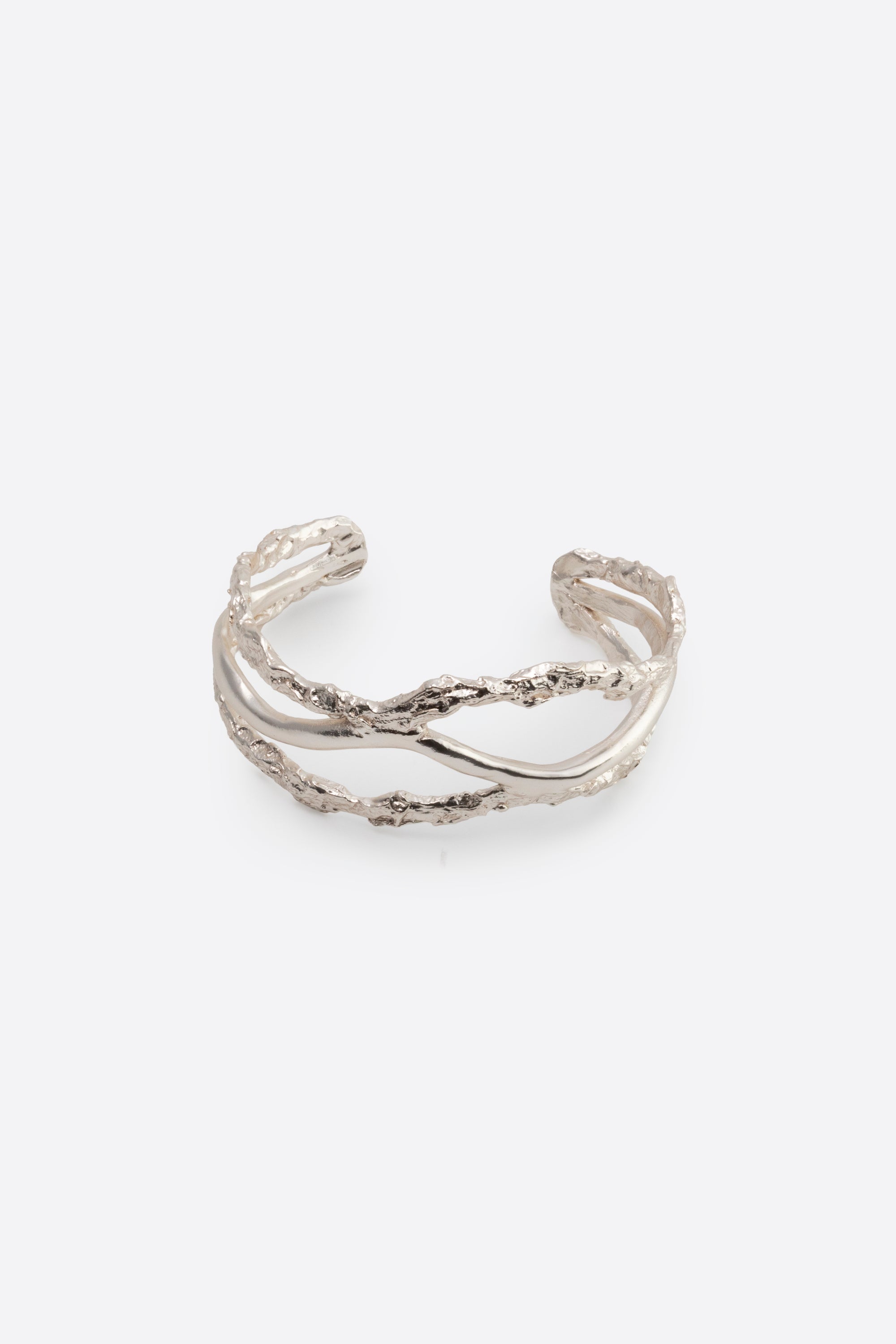 Sculptural silver cuff bracelet with organic texture on white background