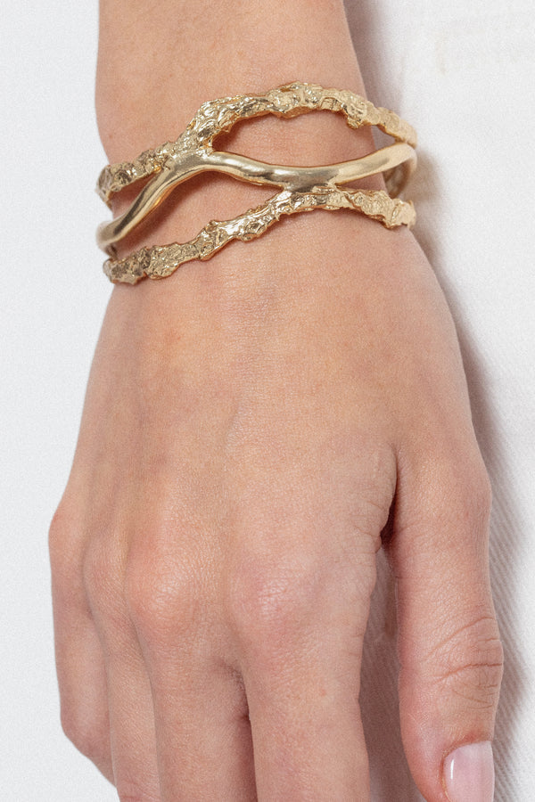 Woman wearing sculptural gold cuff bracelet with organic texture