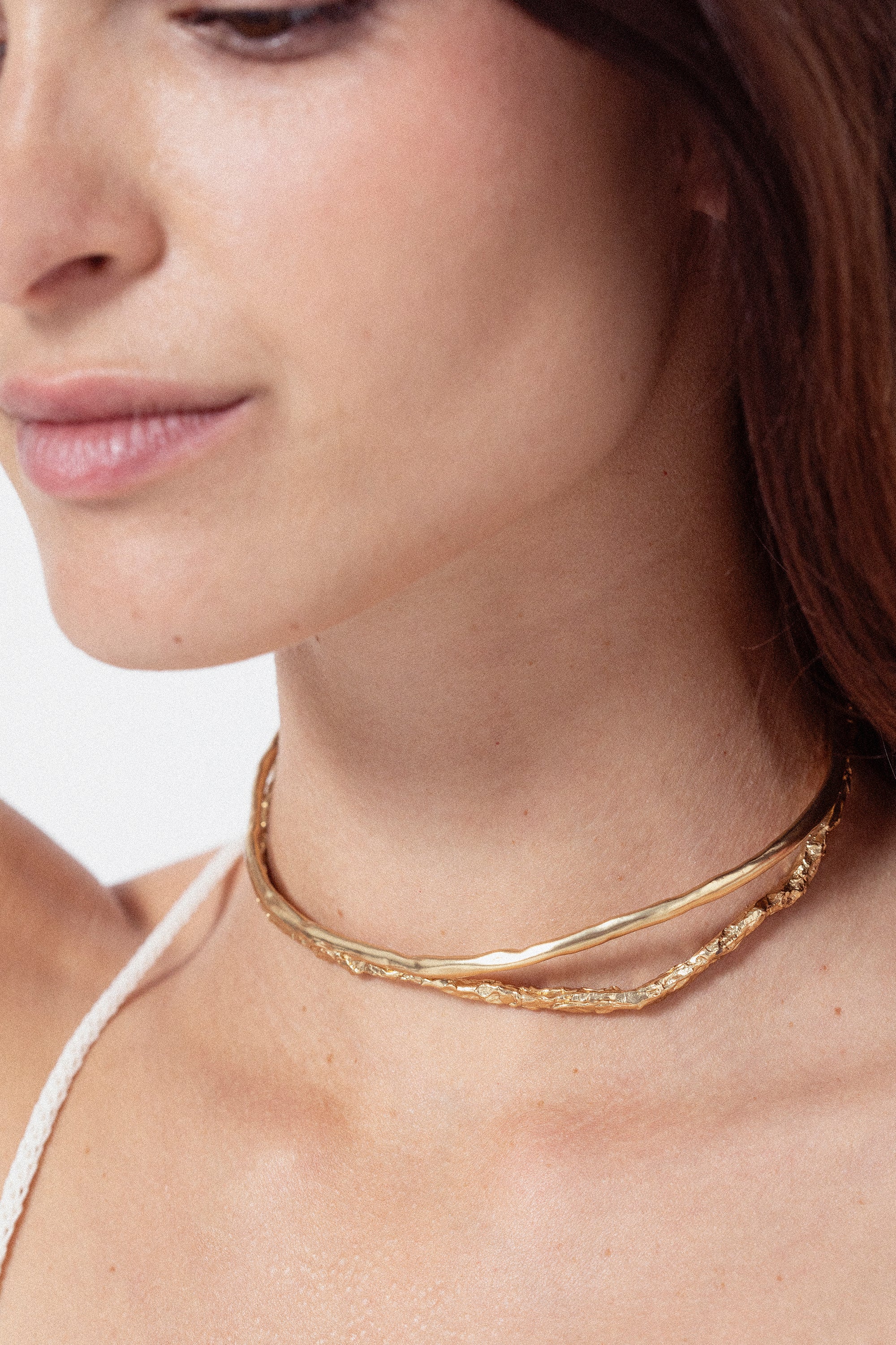 Woman wearing sculptural gold choker necklace with organic design