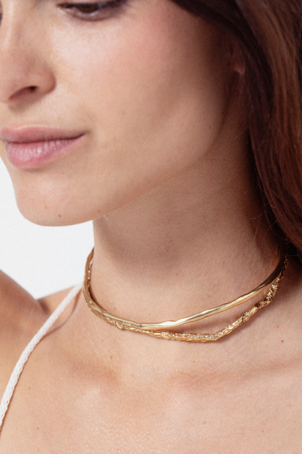 Woman wearing sculptural gold choker necklace with organic design
