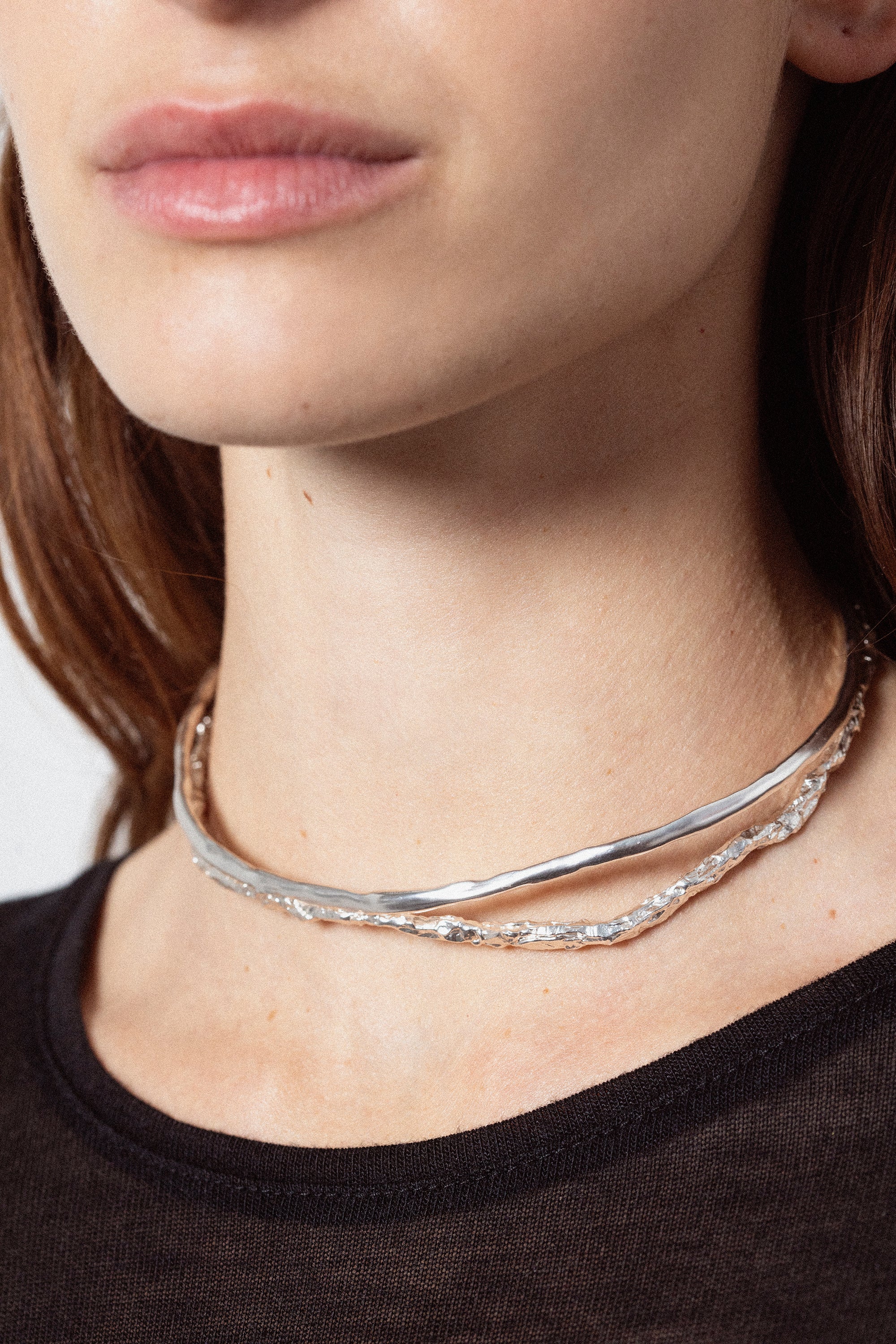 Woman wearing sculptural silver choker necklace with organic design
