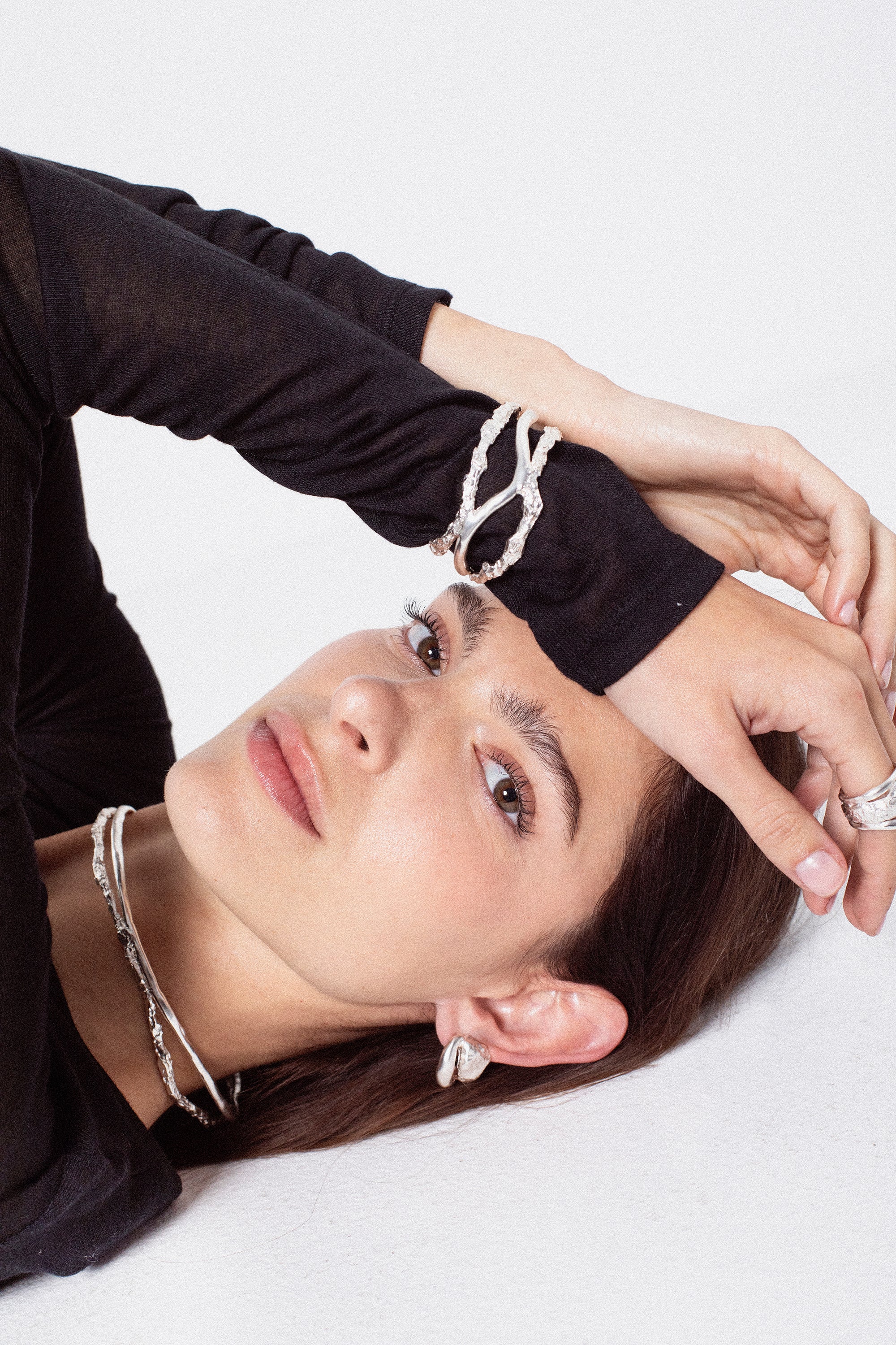 Model styling sculptural silver choker necklace in layered jewelry look