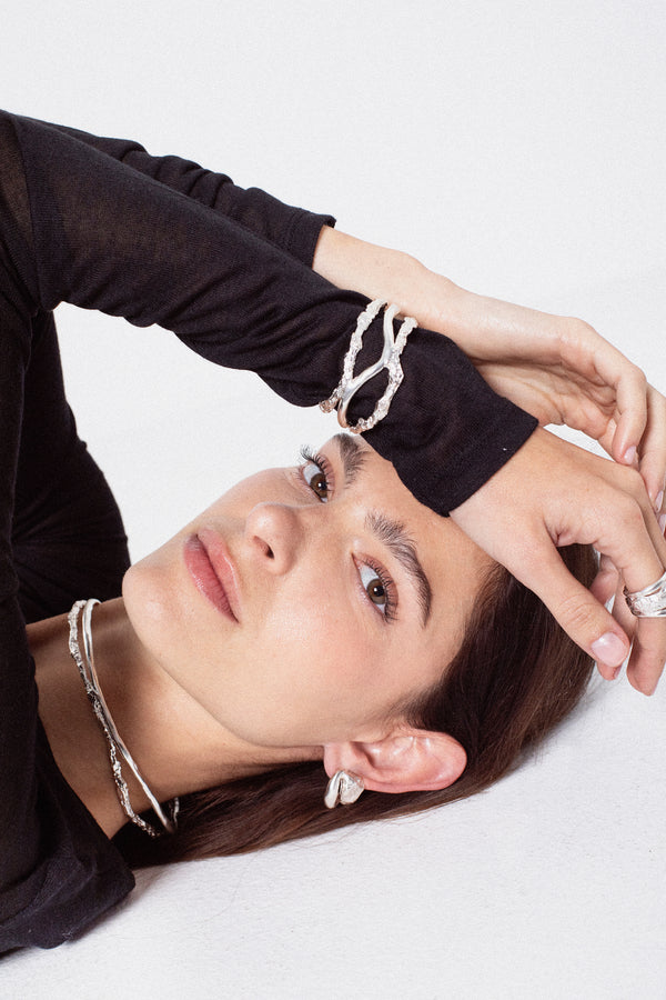 Model styling sculptural silver choker necklace in layered jewelry look