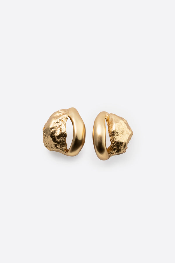 Macro close-up of gold stud earrings with textured surface