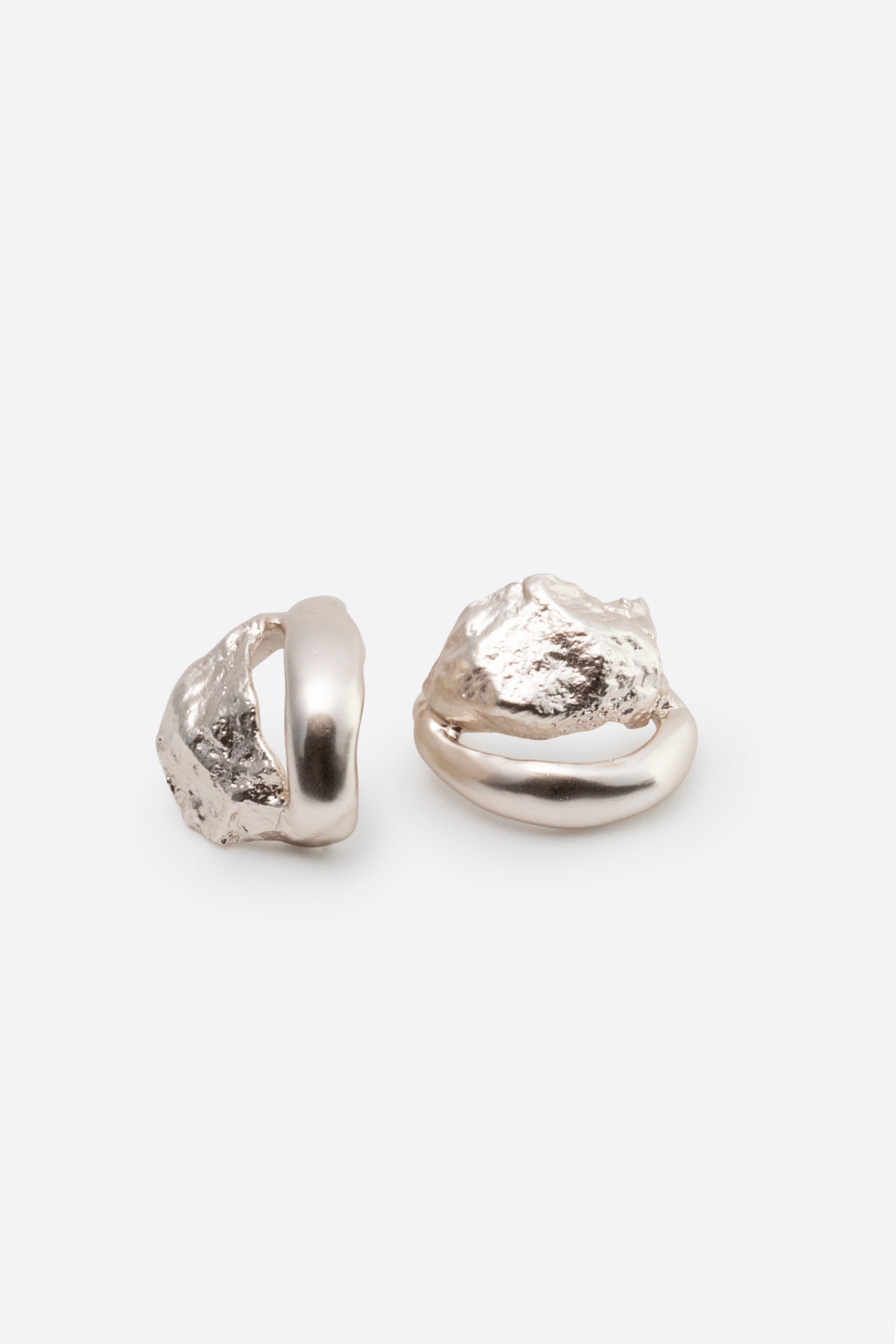 Sculptural silver stud earrings with organic textured design on white background