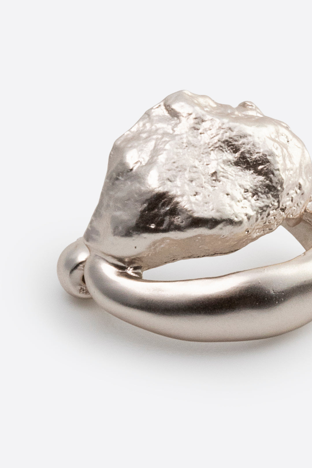 Close-up of sculptural silver earring with textured surface