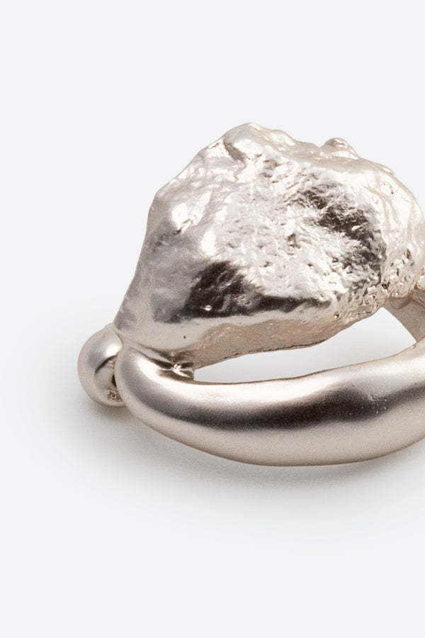 Close-up of sculptural silver earring with textured surface