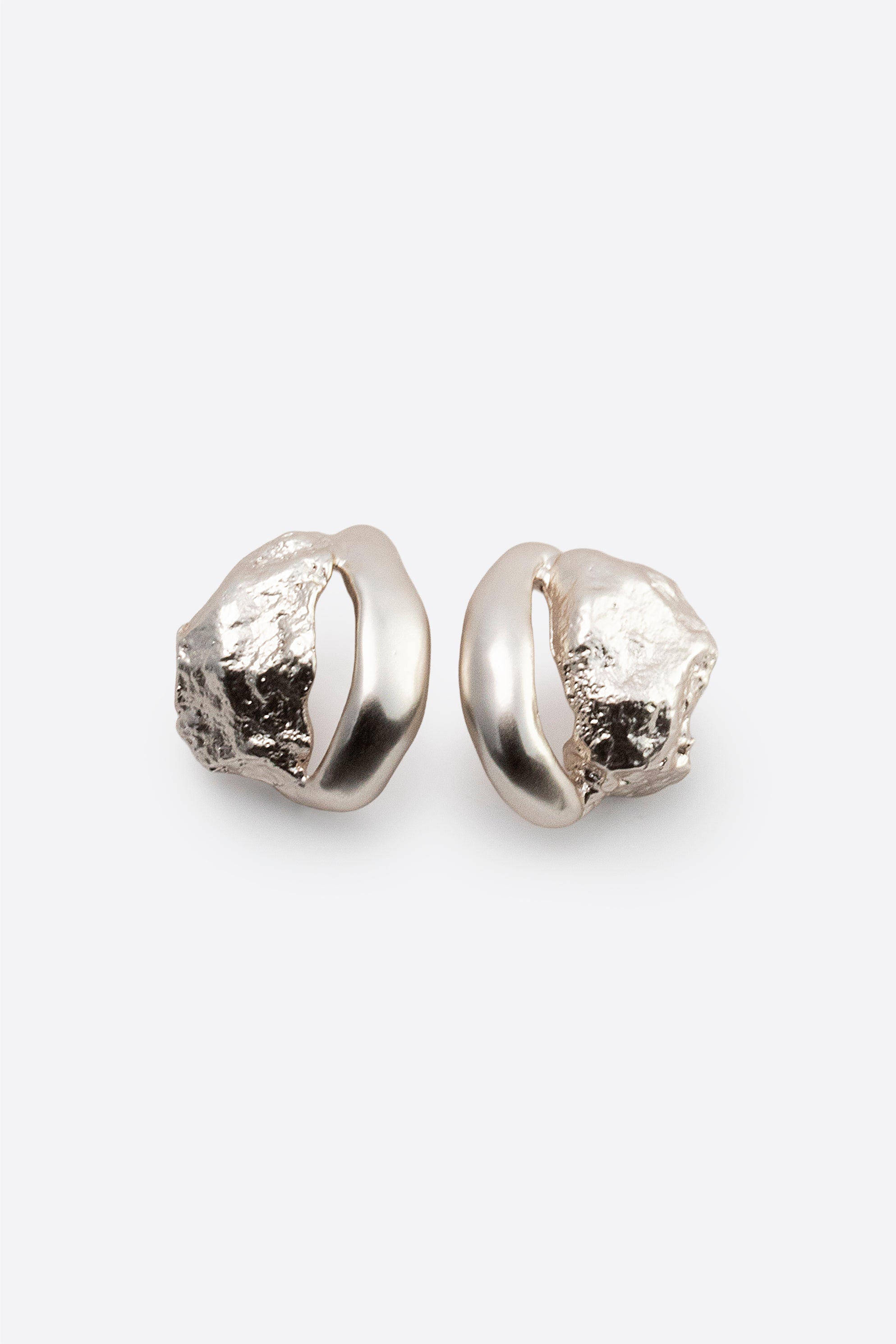 Pair of sculptural silver stud earrings with organic textured design on white background