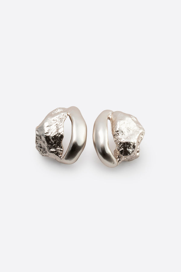 Pair of sculptural silver stud earrings with organic textured design on white background