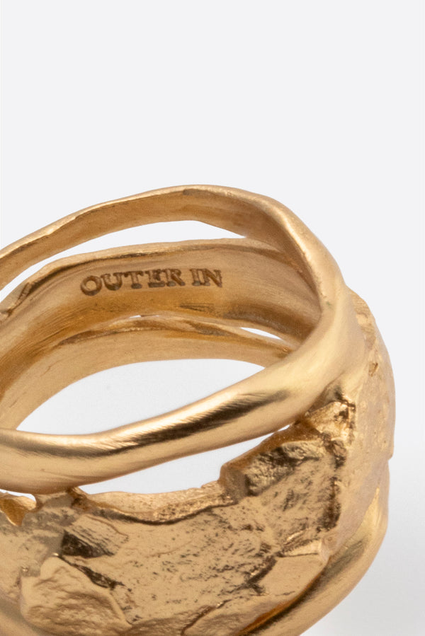 Close-up of sculptural gold ring showing layered organic texture