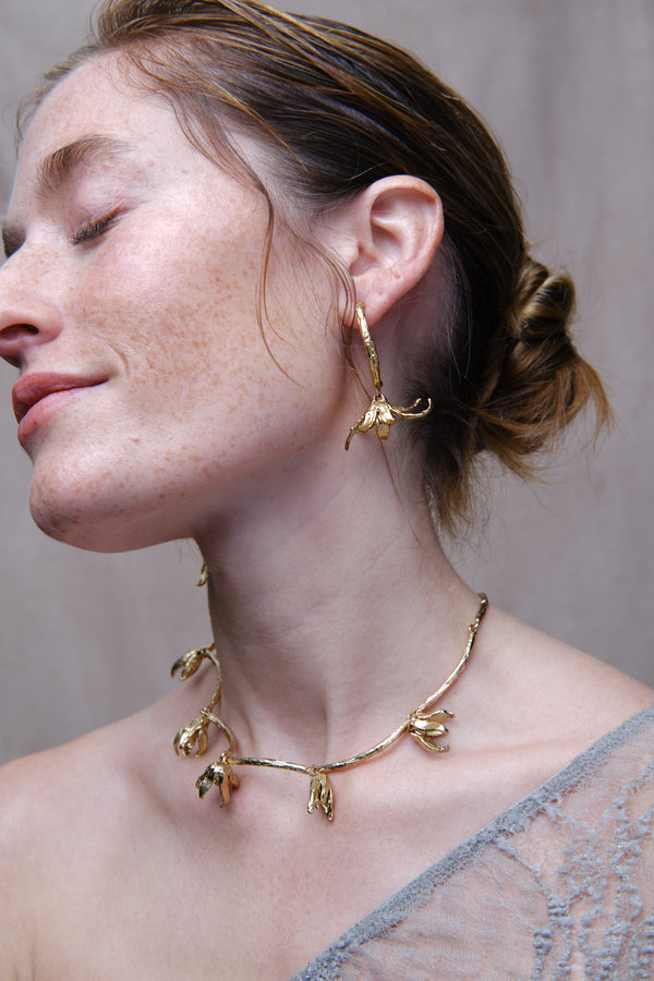 Close-up of woman wearing sculptural gold necklace and matching organic drop earrings