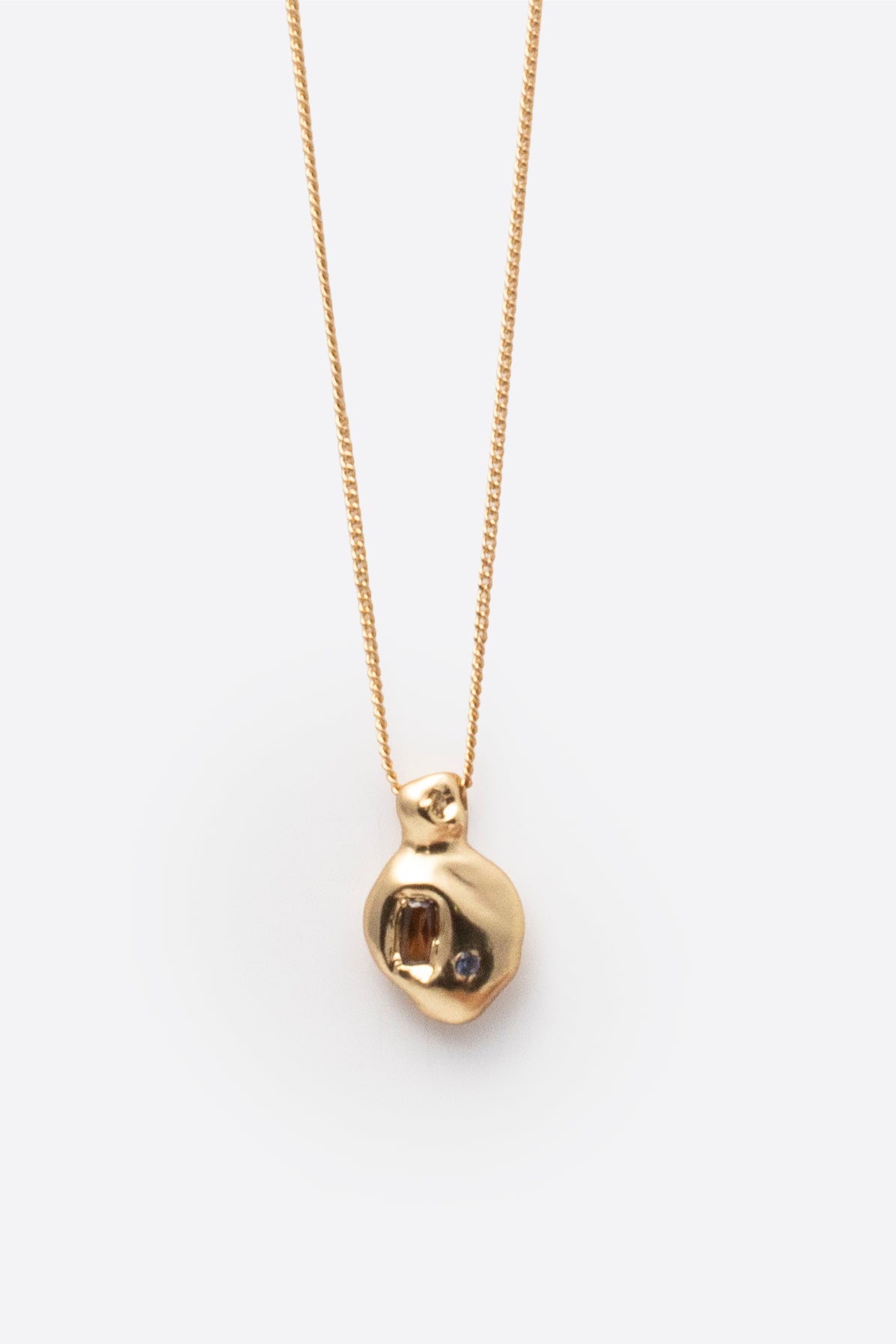 Gold gemstone pendant necklace with organic sculptural pendant