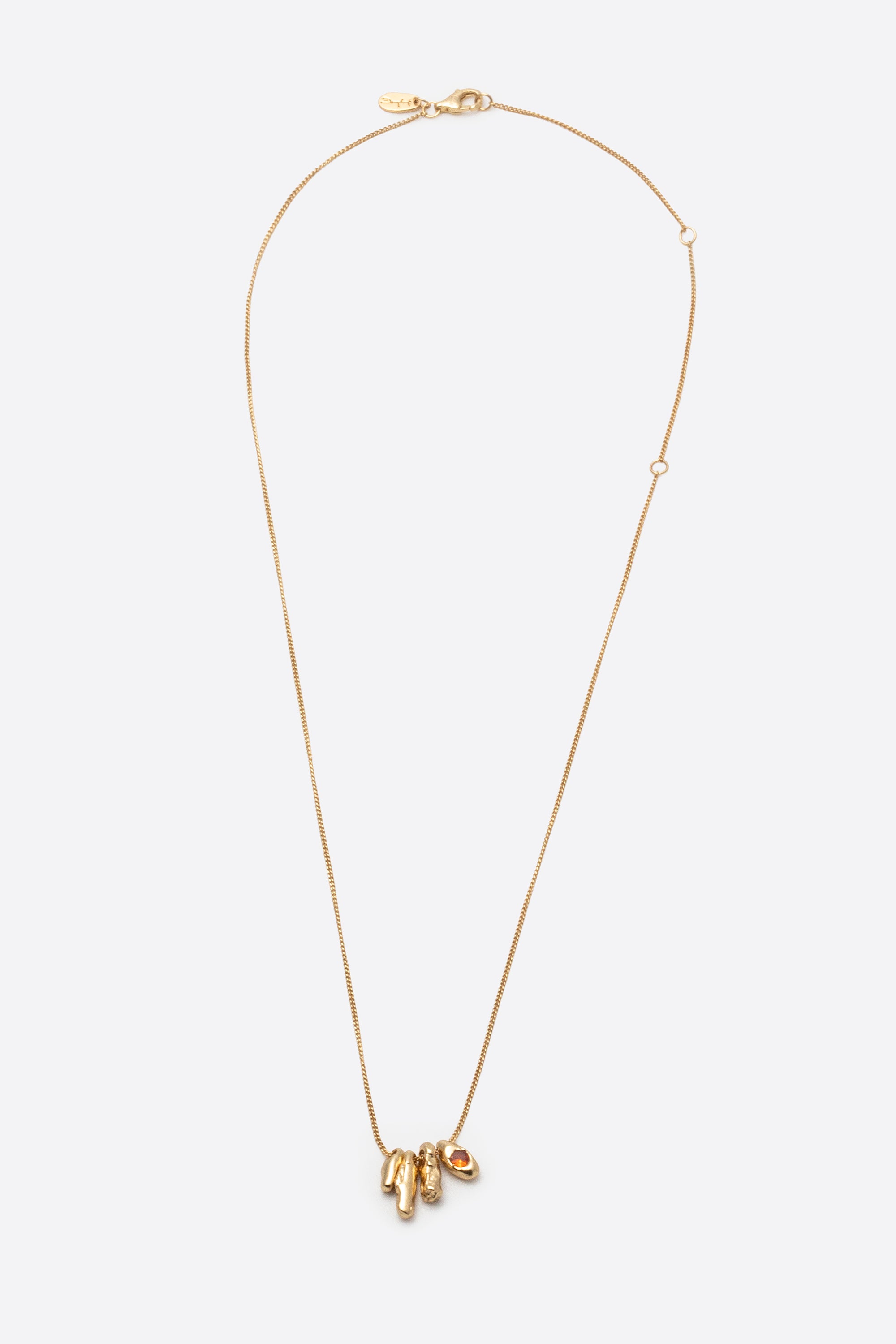 Sculptural gold pendant necklace with orange gemstone on white background