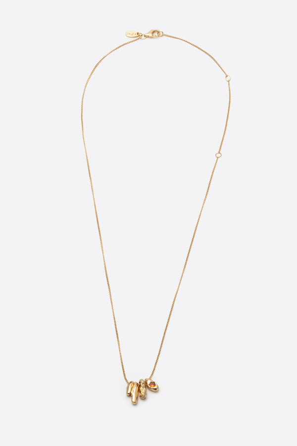 Sculptural gold pendant necklace with orange gemstone on white background
