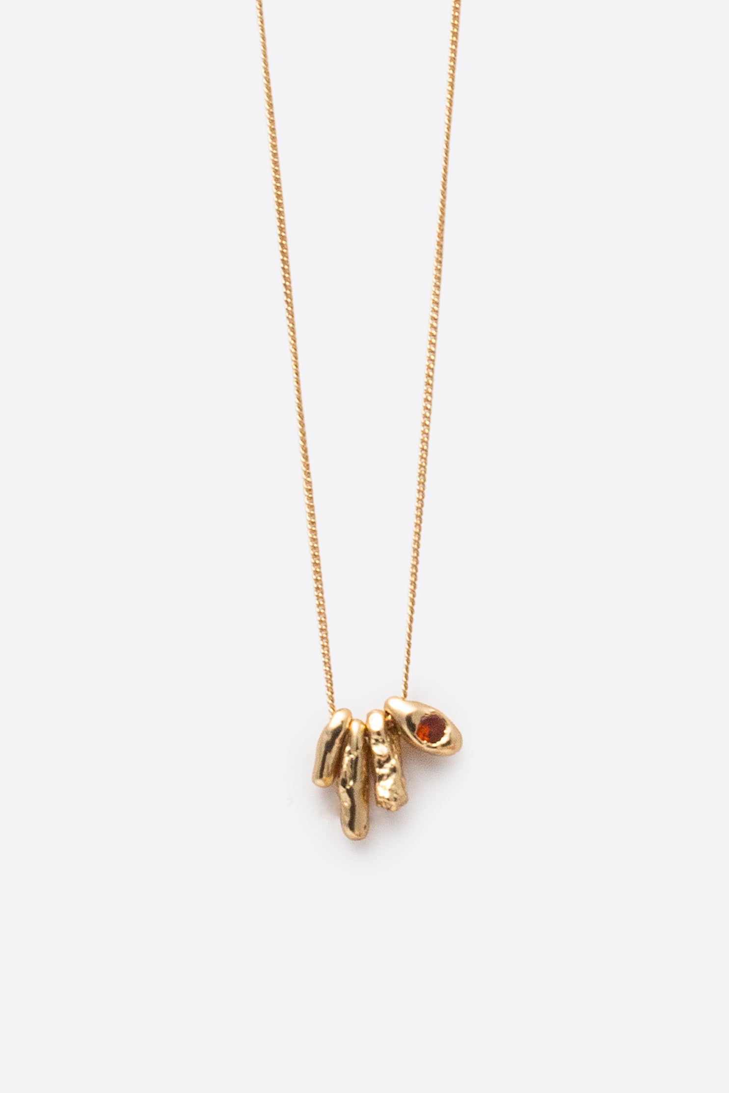 Gold pendant necklace with sculptural charm and orange gemstone detail