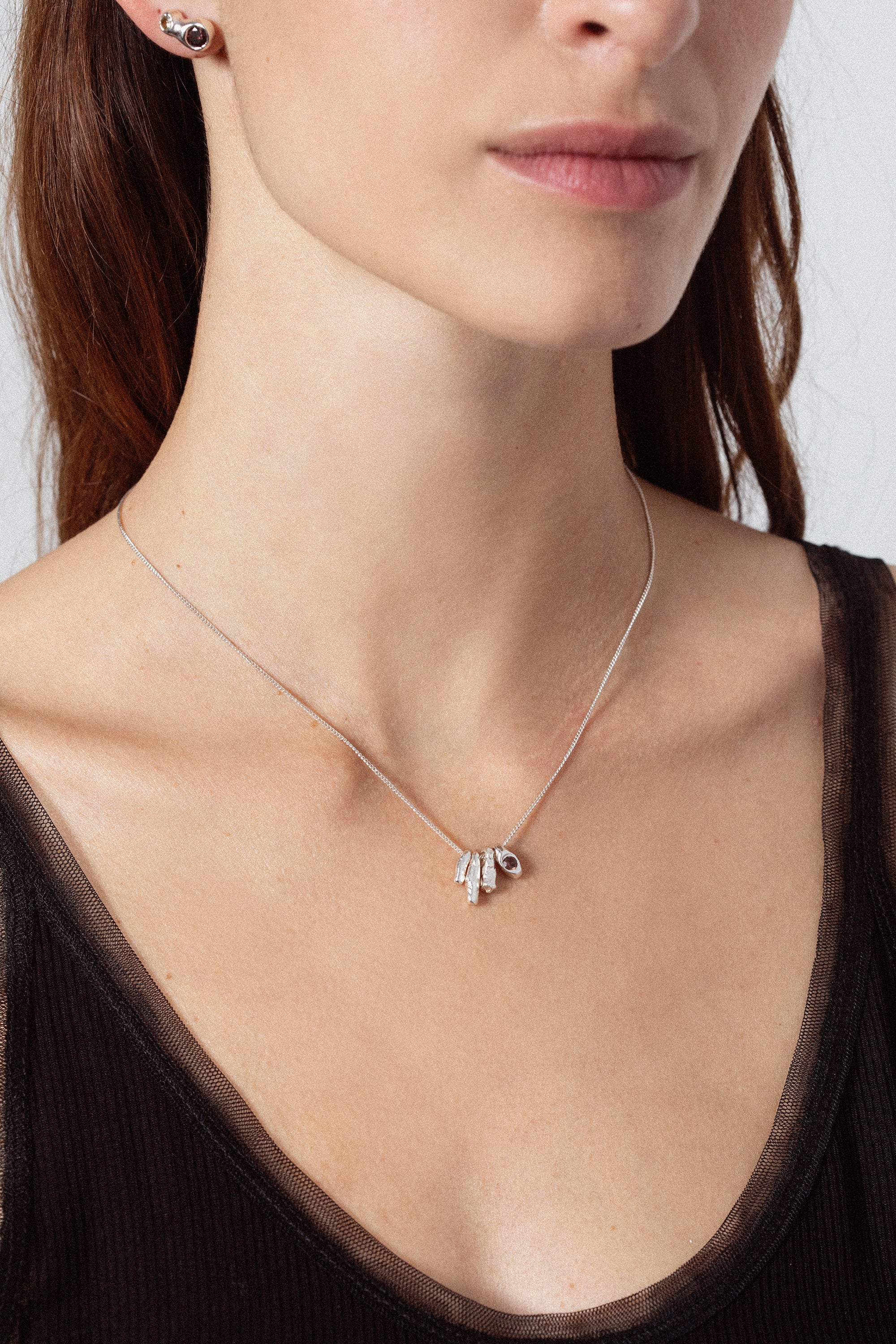 Woman wearing sculptural silver pendant necklace with dark gemstone