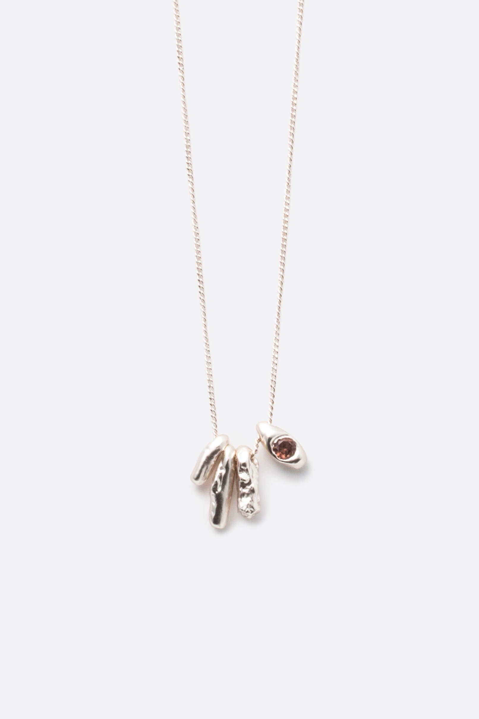 Close-up of sculptural silver pendant necklace with dark gemstone detail