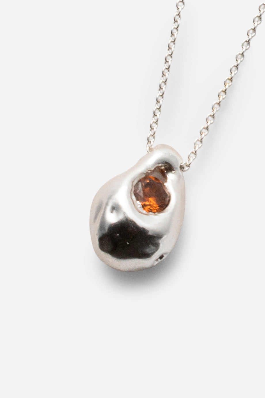 Close-up of silver pendant necklace with dark gemstone and sculptural setting