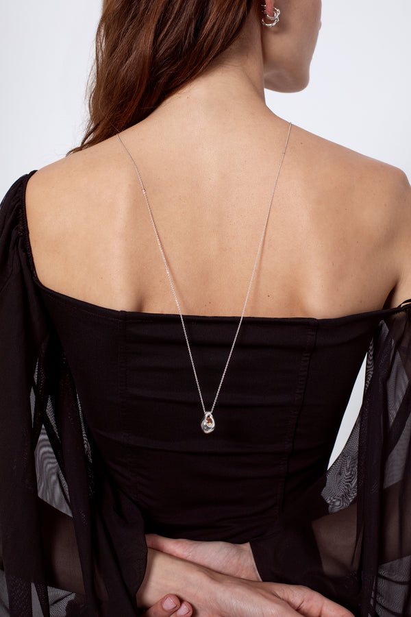 Back view of woman wearing long silver pendant necklace