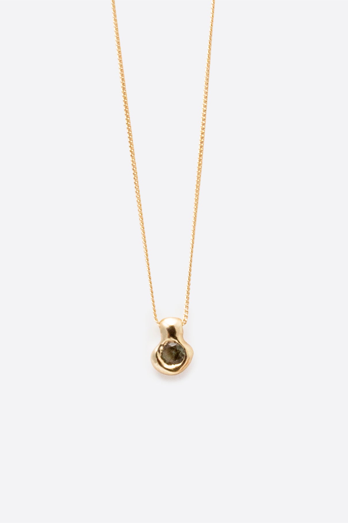 Sculptural gold pendant necklace with dark gemstone on fine chain