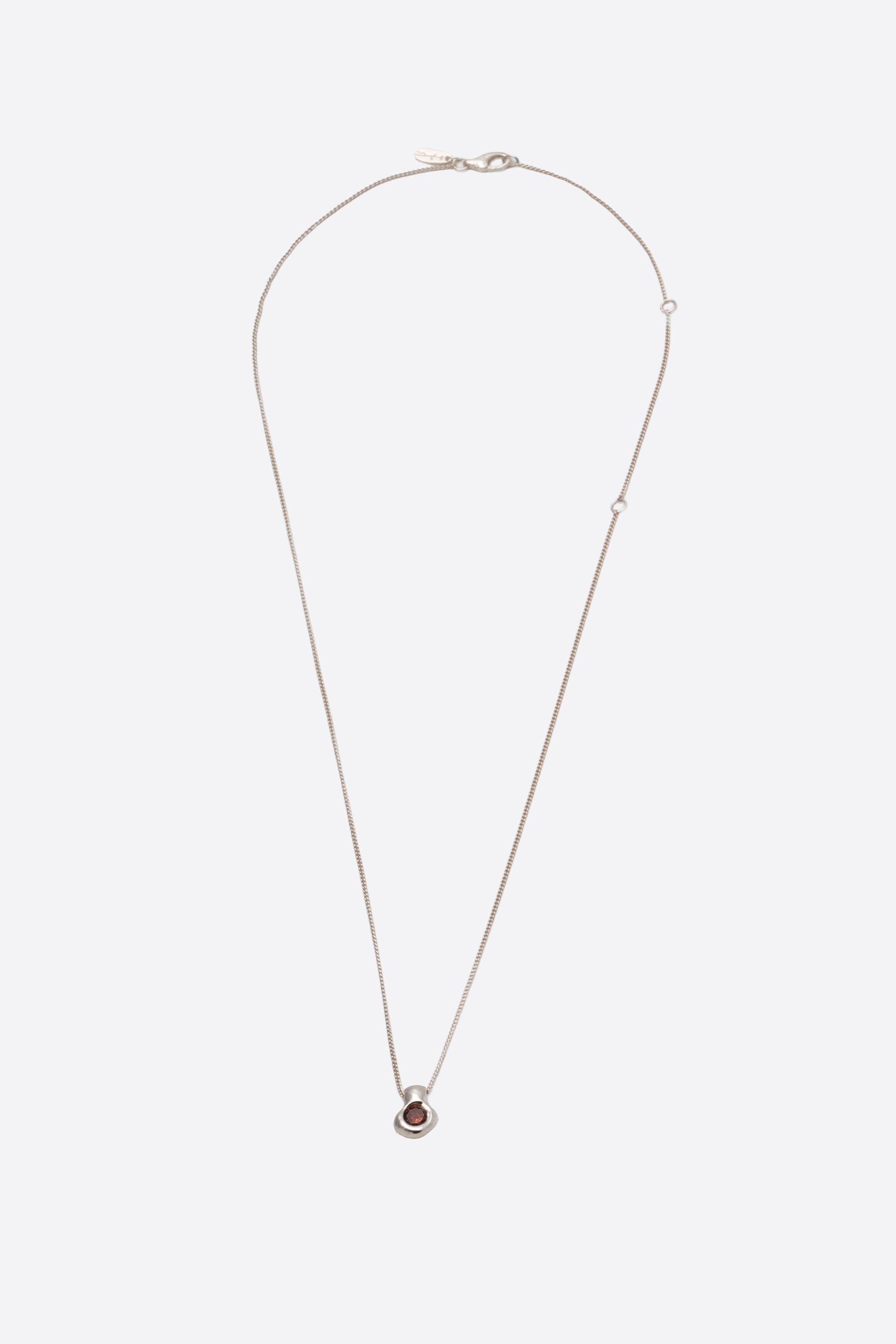 Sculptural silver pendant necklace with dark gemstone on fine chain