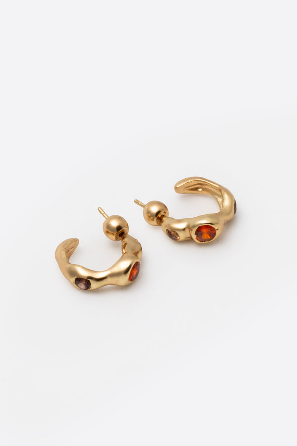 Sculptural gold gemstone huggie earrings with organic design on white background