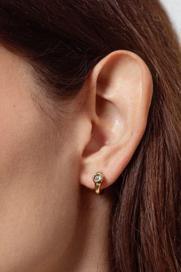Woman wearing sculptural gold gemstone stud earrings