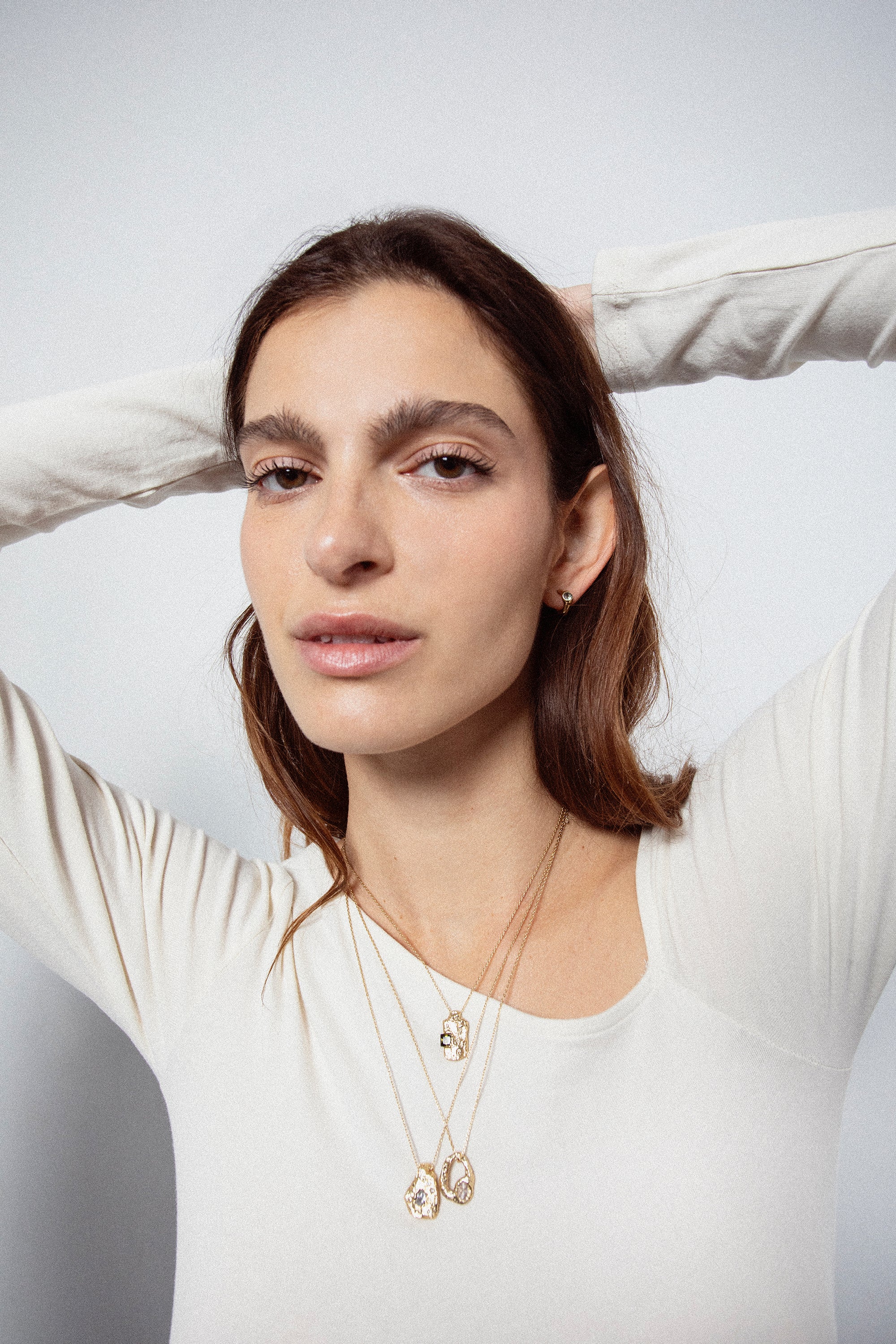 Model styling sculptural gold gemstone stud earrings with matching jewelry