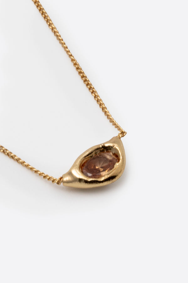 Close-up of gold gemstone pendant necklace with sculptural setting